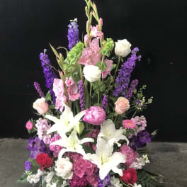 Tall floral arrangement with white lilies, pink roses, and purple blooms