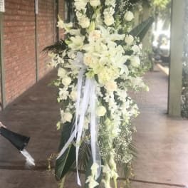 Tall white floral standing spray with lilies and roses on an easel