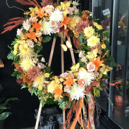 Large floral wreath on an easel with orange, yellow, and pink flowers