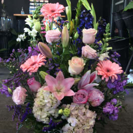 Large mixed flower basket with pink lilies, roses, gerbera daisies, and purple blooms