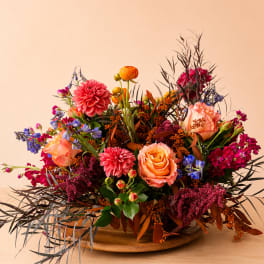 Colorful mixed flower arrangement in a low wooden bowl