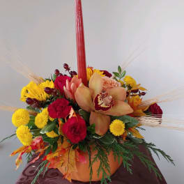 Autumn floral centerpiece with red candle in a pumpkin vase
