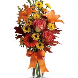 Orange lilies and roses with yellow daisies in a glass vase