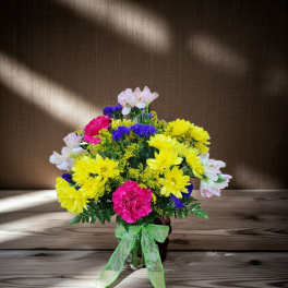 Bright mixed bouquet in a glass vase with a green ribbon