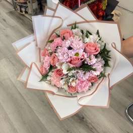 Pink roses and daisies wrapped in white paper with blush trim