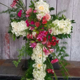 Cross-shaped floral arrangement with white hydrangeas and pink flowers
