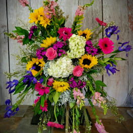 Large colorful standing floral spray with sunflowers, gerberas, roses, and irises