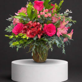 Pink roses and mixed blooms arranged in a glass vase