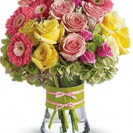 Pink and yellow roses with pink gerbera daisies in a glass vase