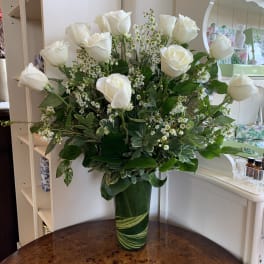 White roses and small white filler flowers in a green glass vase.