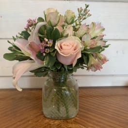 Pink rose and lily bouquet in a glass jar vase