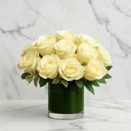 Cream roses arranged in a dark green glass vase