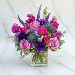 Purple and pink rose bouquet in a clear glass vase
