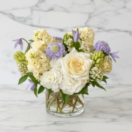 White and lavender flowers arranged in a clear glass vase
