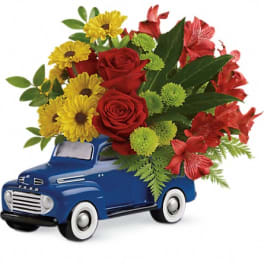 Red and yellow flower arrangement in a blue toy truck