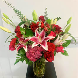 Red roses and pink lilies arranged in a glass vase
