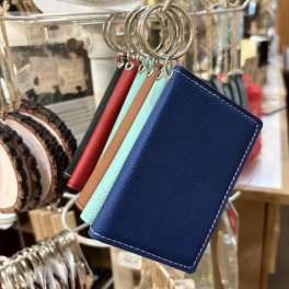 Leather keychain wallet cards hang on a display rack in a shop