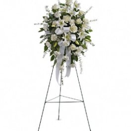 White floral standing spray on an easel with ribbon streamers