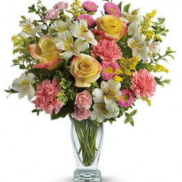 Mixed bouquet of roses, carnations, and white alstroemeria in a glass vase