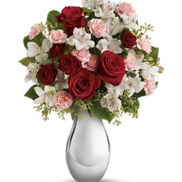 Red roses, white alstroemeria, and pink carnations in a silver vase