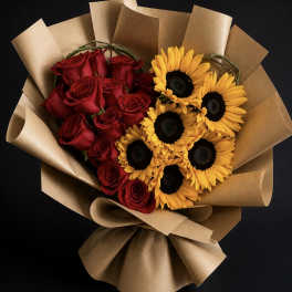 Bouquet of red roses and yellow sunflowers wrapped in brown paper