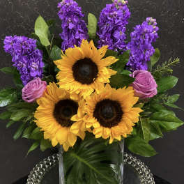 Sunflowers, purple stock, and pink roses in a clear glass vase