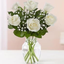 White roses in a clear glass vase with baby's breath