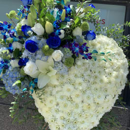 Heart-shaped floral tribute with white chrysanthemums and blue flowers