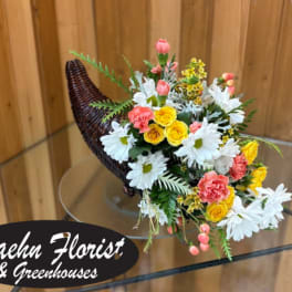 Mixed bouquet in a woven horn-shaped basket with white daisies and pink and yellow flowers