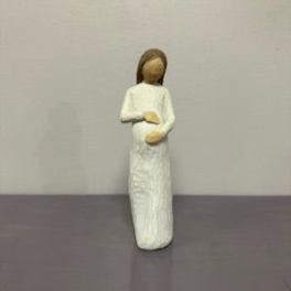 Small angel figurine in a white dress standing on a plain surface