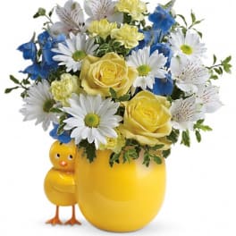 Yellow and blue flower arrangement in a chick-shaped vase