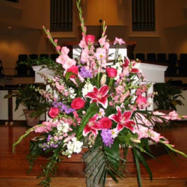 Large pink and white floral arrangement in a stone vase
