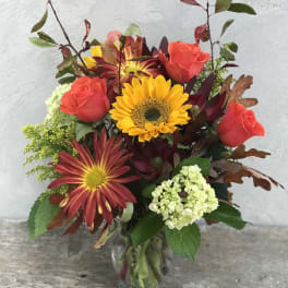 Mixed bouquet of roses, sunflowers, and chrysanthemums in a glass vase