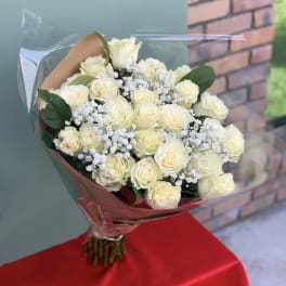 Bouquet of cream roses with baby's breath wrapped in clear plastic
