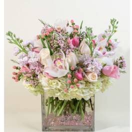 Low pink and white flower arrangement with orchids and roses in a square glass vase
