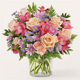 Bouquet of peach roses, pink lilies, and purple daisies in a glass vase