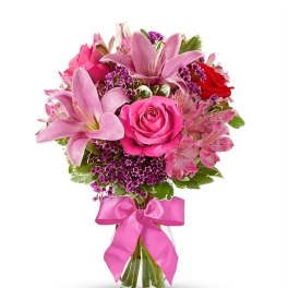 Pink roses and lilies in a glass vase with a pink ribbon