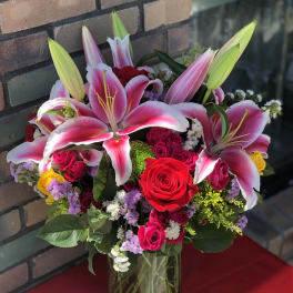 Bouquet of pink lilies and red roses in a glass vase