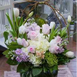 Pink and white tulips with roses in a round glass vase