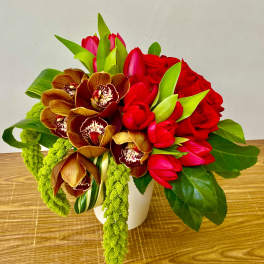 Bouquet of red roses, red tulips, and orchids in a white vase