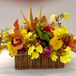Bright yellow and orange floral arrangement in a rectangular wooden container
