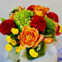 Bouquet of orange and red flowers in a green glass vase