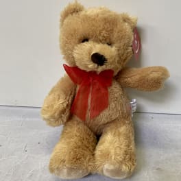Tan teddy bear with a red ribbon bow