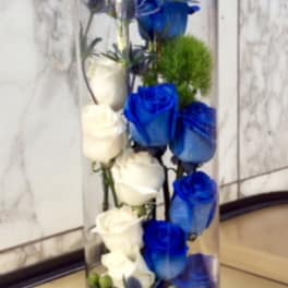Tall glass vase with white and blue roses and small accent flowers