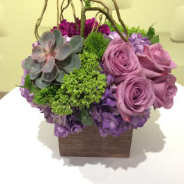 Purple roses and succulents in a wooden box with twig handles