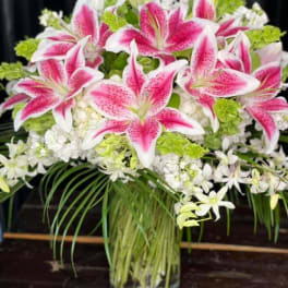 Pink stargazer lilies and white flowers in a glass vase