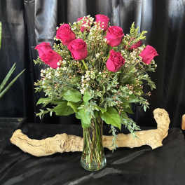 Pink roses in a clear glass vase with small white filler flowers