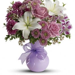 Bouquet of pink roses, white lilies, and purple flowers in a lavender vase