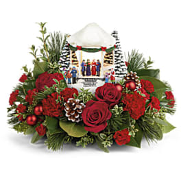 Christmas floral arrangement with red roses and pinecones around a small nativity scene