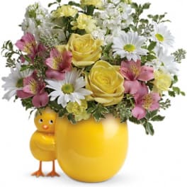Yellow floral arrangement in a chick-shaped vase with daisies and roses